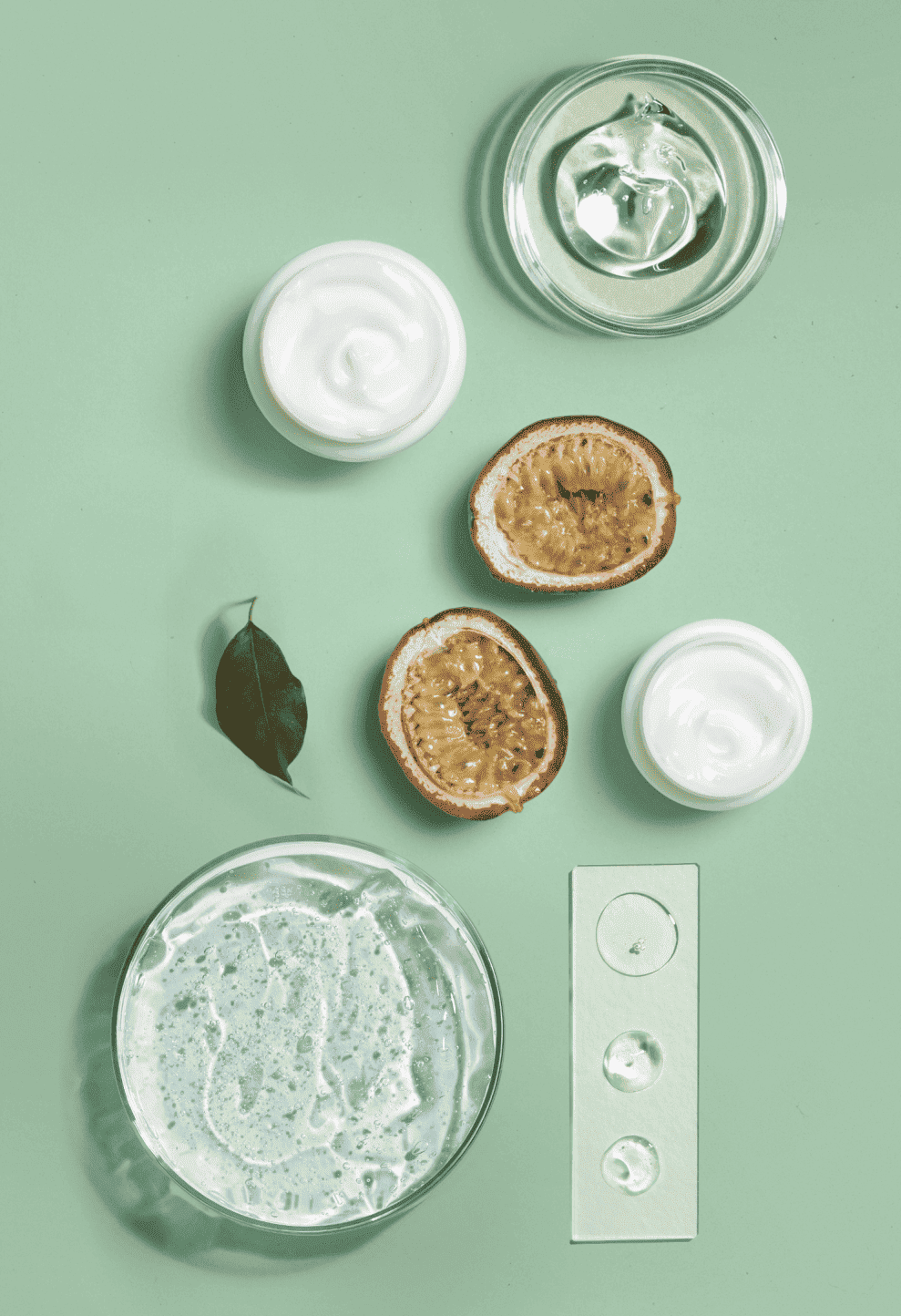 Samenstelling van natuurlijke actieve ingrediënten: gels, crèmes, passievrucht en cosmetische texturen op een groene achtergrond