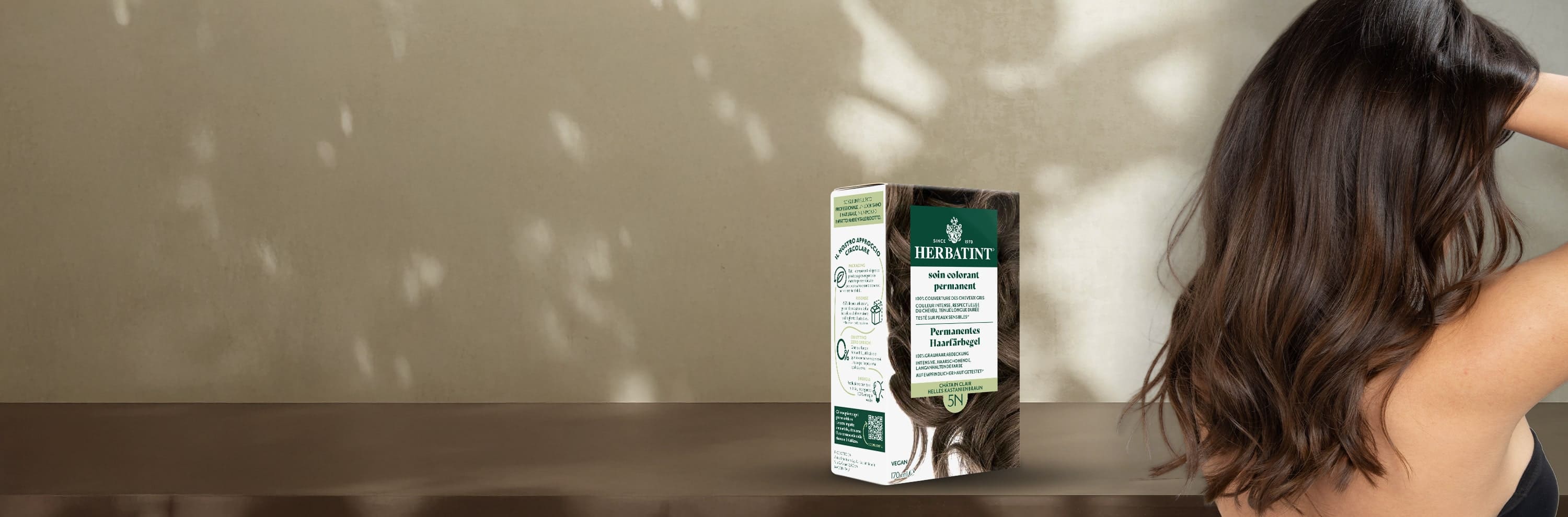 Herbatint Dauerhafte Colorationsgel-Packung in Hellbraun 5N neben einer Frau mit gesundem, glänzendem Haar in einem natürlichen hellbraunen Ton
