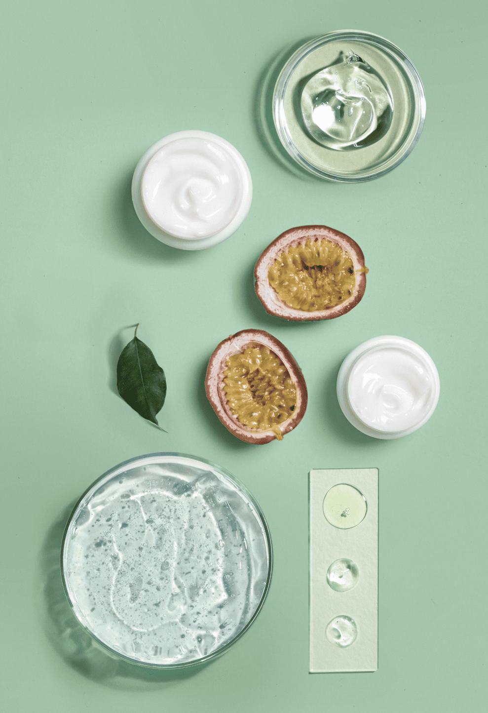 Composizione di ingredienti attivi naturali, tra cui gel, creme, frutto della passione e texture cosmetiche su sfondo verde