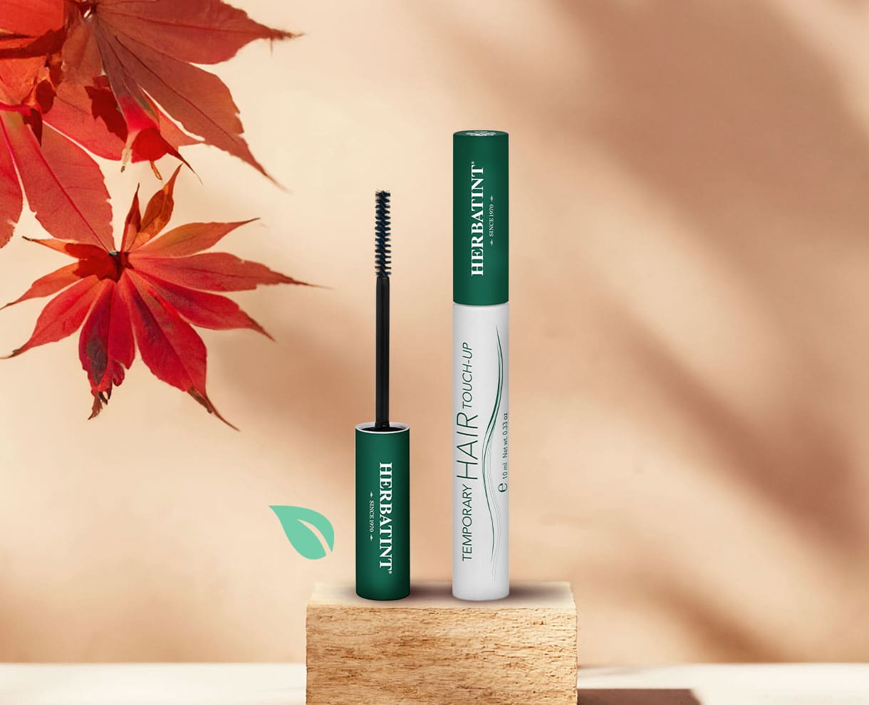 Herbatint Temporary Hair Touch-Up Haarmascara auf einem Holzsockel präsentiert, mit herbstlichem Hintergrund und roten Blättern