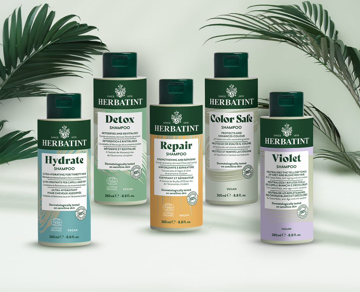 Cinco frascos de champô Herbatint para pele e couro cabeludo sensíveis – variantes Hydrate, Detox, Repair, Color Safe e Violet sobre fundo claro