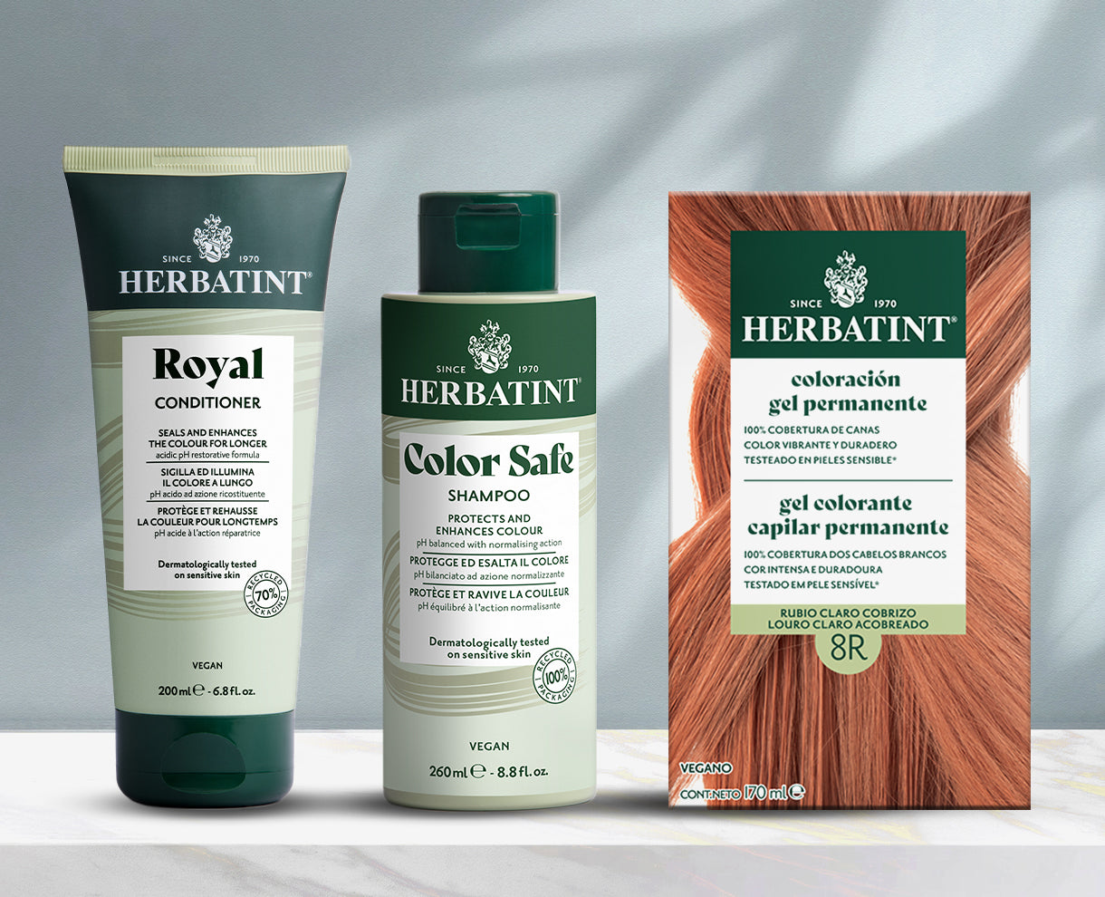 Línea de productos Herbatint sobre fondo gris, incluidos champú, acondicionador y gel colorante permanente sobre una mesa de mármol.
