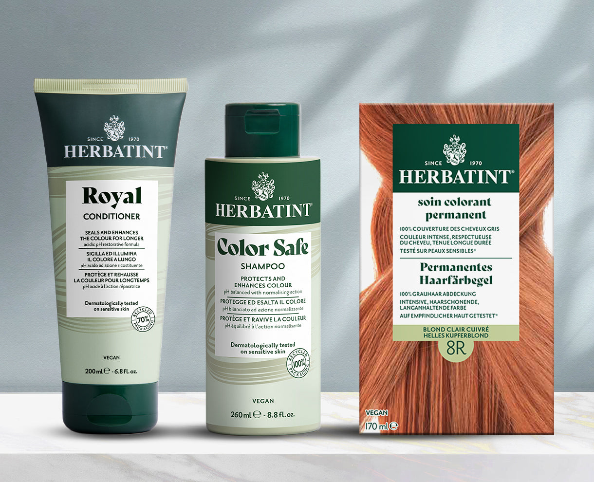 Herbatint-Produktlinie auf grauem Hintergrund präsentiert, einschließlich Shampoo, Conditioner und permanentem Färbegel auf einem Marmortisch.