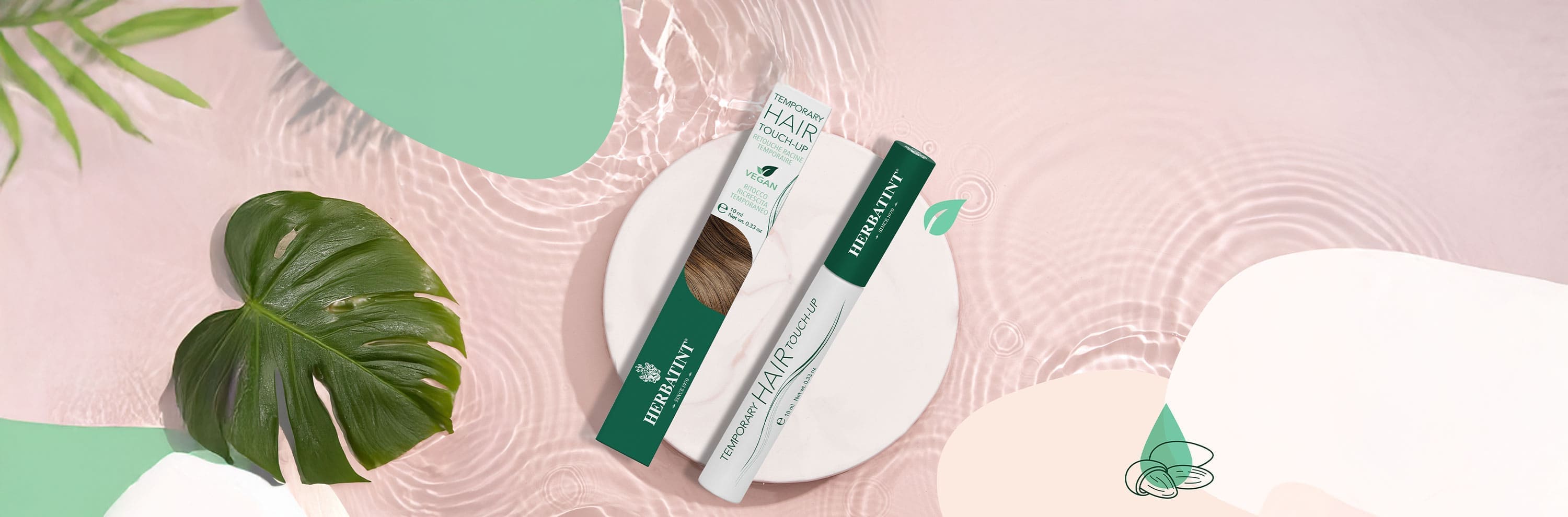 Máscara capilar Herbatint para cobertura temporal de canas, colocada sobre una superficie circular blanca con agua y hojas tropicales decorativas sobre fondo rosa; envase verde y blanco con la etiqueta “Temporary Hair Touch-Up”