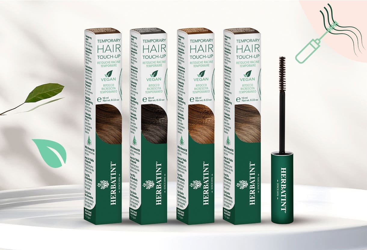 Linha completa de máscaras de cabelo Herbatint em quatro tons com aplicadores de escova e embalagem verde, expostas sobre uma mesa branca num ambiente natural com iluminação suave