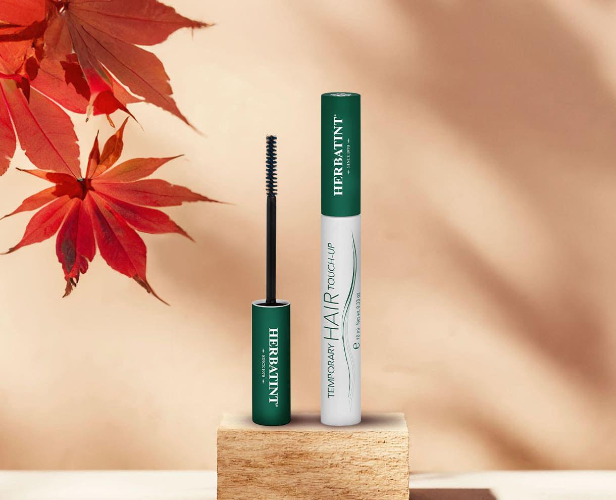 Mascara pour cheveux Herbatint Temporary Hair Touch-Up présentée sur un support en bois avec un décor automnal de feuilles rouges