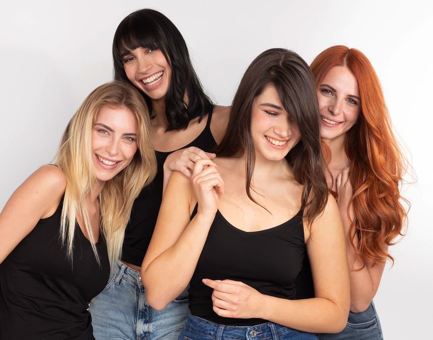 Quatre femmes souriantes aux cheveux blonds, noirs, bruns et roux montrant différents résultats de coloration