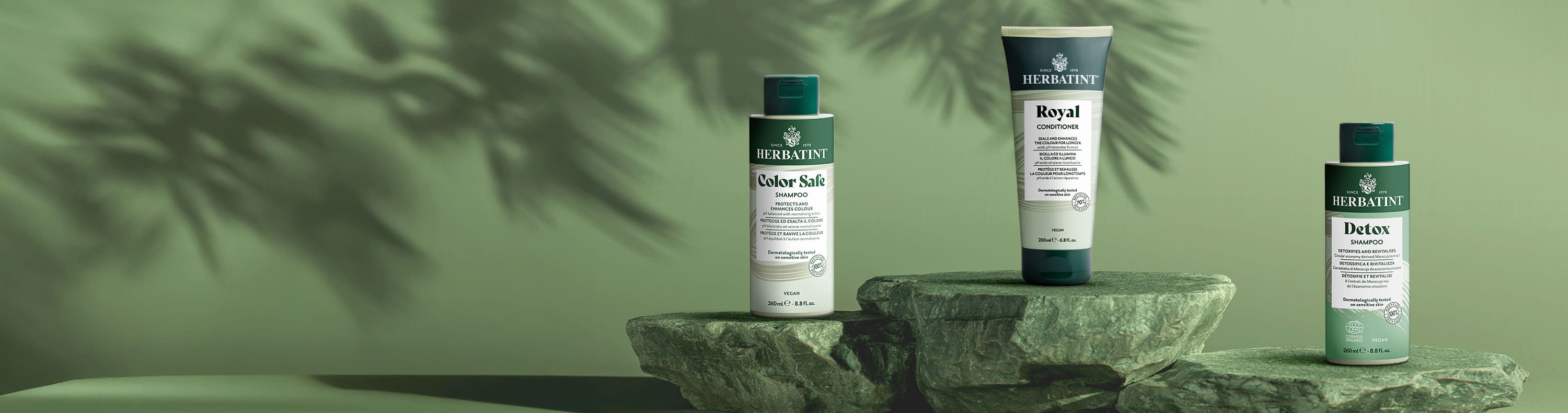 Linea hair care Herbatint con shampoo Color Safe, balsamo Royal e shampoo Detox posizionati sopra delle pietre su sfondo verde naturale