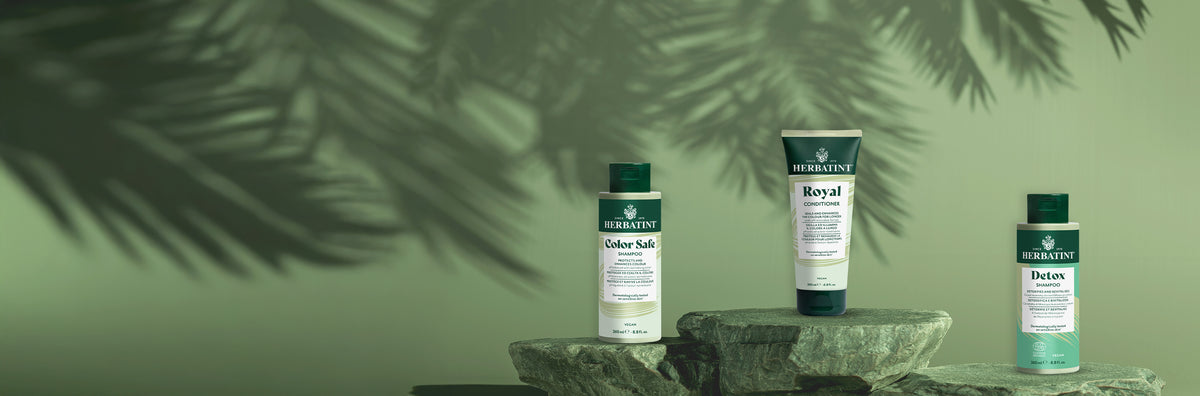 Herbatint Color Safe Shampoo, Royal Conditioner und Detox Shampoo auf Natursteinen arrangiert, als Symbol für Haarschutz, Pflege und Entgiftung