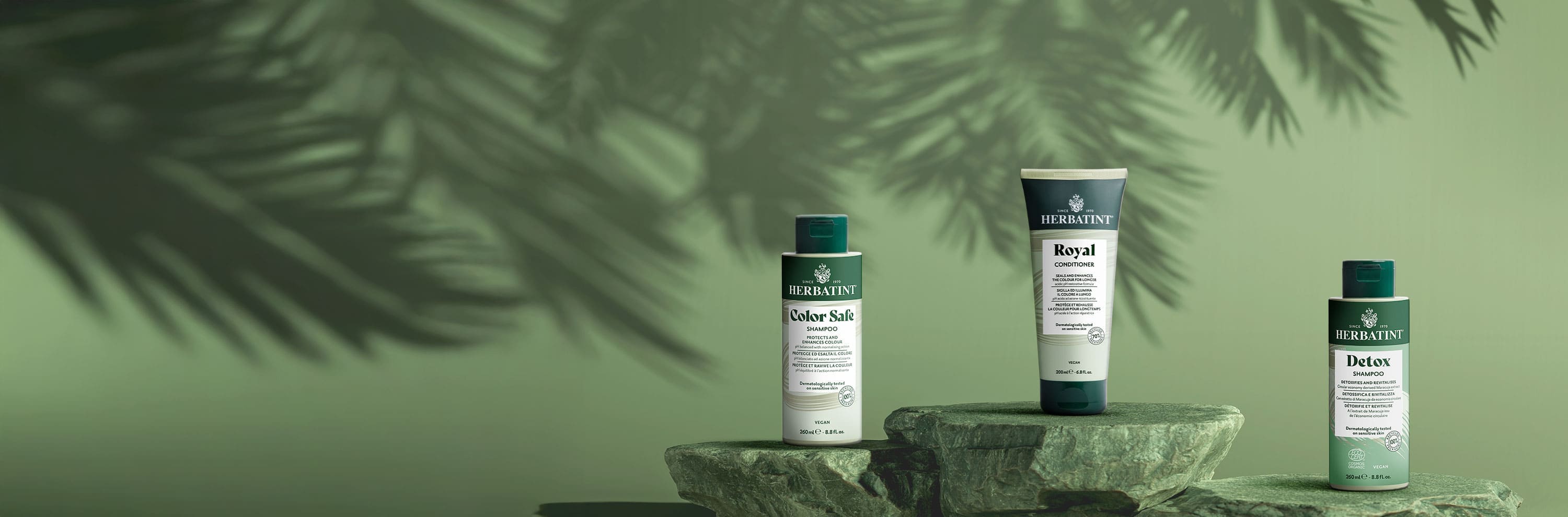 Champô Color Safe, condicionador Royal e champô Detox da Herbatint dispostos sobre pedras naturais, representando proteção, nutrição e desintoxicação do cabelo