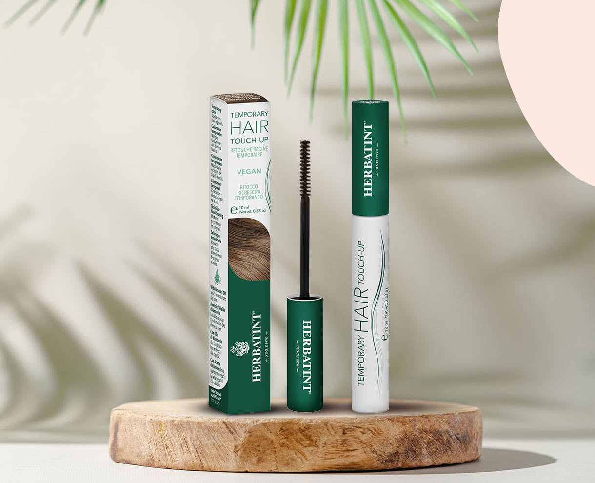 Produit Herbatint Temporary Hair Touch-Up pour la retouche des racines, avec flacon et emballage visibles sur support en bois, décoration naturelle en arrière-plan