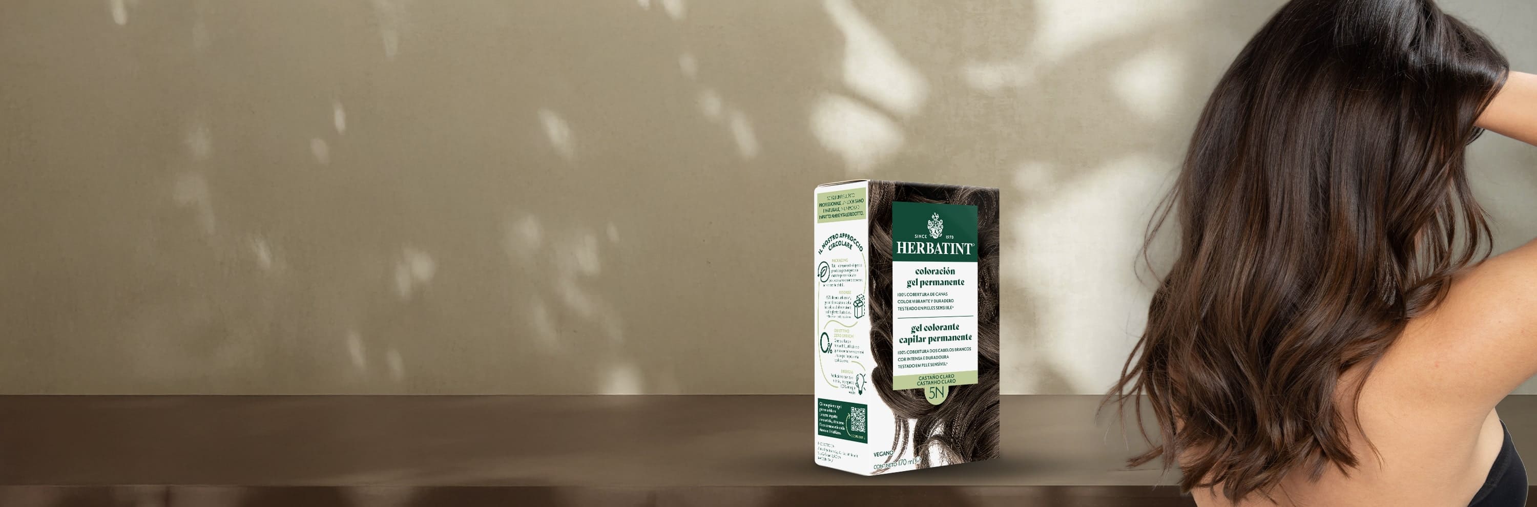 Embalagem do gel de coloração permanente Herbatint castanho claro 5N ao lado de uma mulher com cabelo saudável e brilhante num tom castanho claro natural