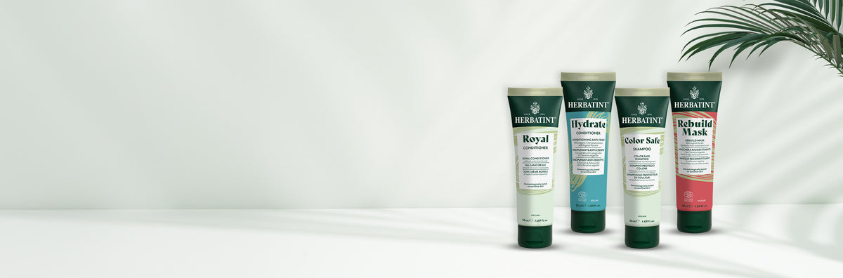 Vier Herbatint reisformat tubes op een lichte achtergrond – Color Safe shampoo, Hydrate en Royal conditioners, Rebuild Mask voor behandeld en gevoelig haar