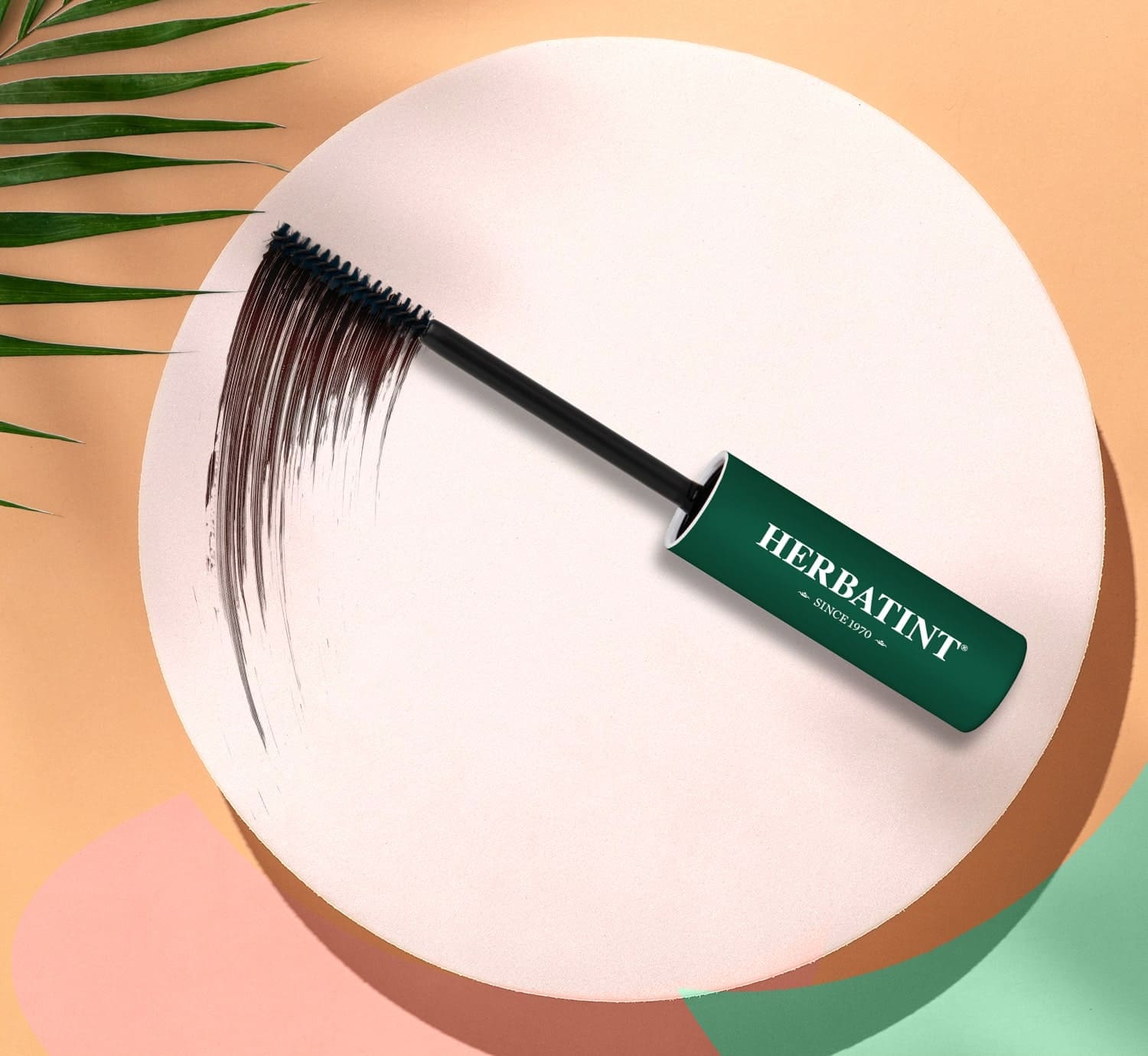 Herbatint Haarmascara-Pinsel mit dunkelgrünem Griff und weißem Logo, dargestellt auf einem hellen kreisförmigen Hintergrund, während er braune Farbe in einer gleichmäßigen, präzisen Bewegung aufträgt
