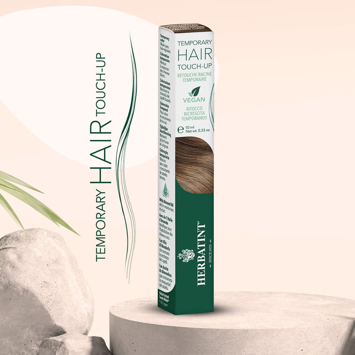 Herbatint Temporary Hair Touch-Up Produktverpackung für temporäre Ansatzkorrektur, platziert auf einer runden Basis mit Bambusblättern und natürlichen Steinen im Hintergrund